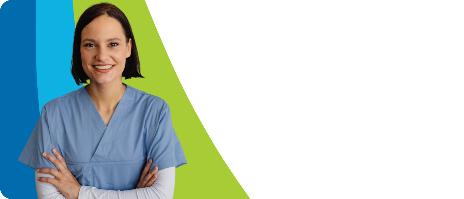 A happy female nurse in blue scrubs stands with her arms crossed.