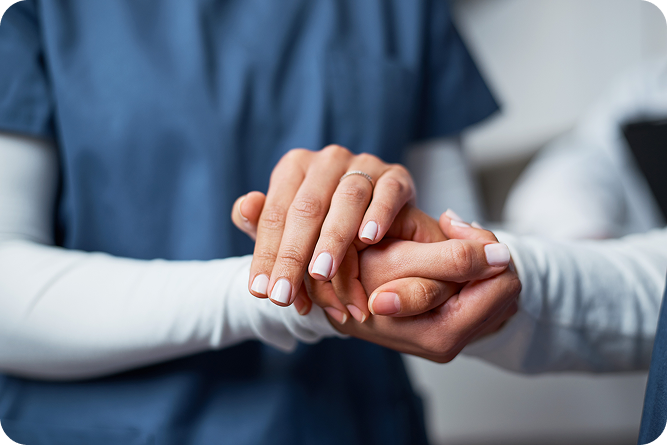 A close-up of a caregiver's hands gently holding a senior person's hands.