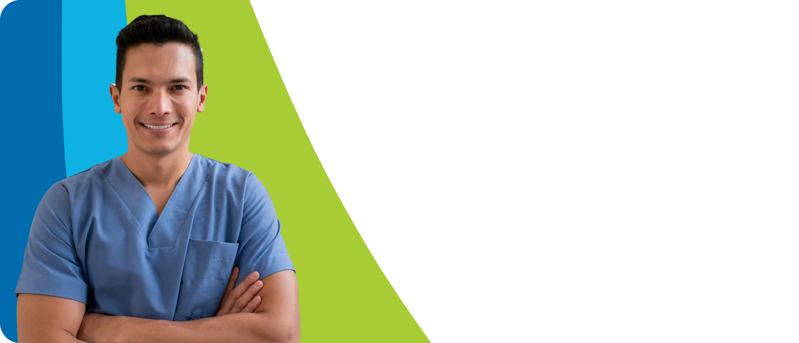 A smiling male caregiver in blue scrubs stands with his arms crossed.
