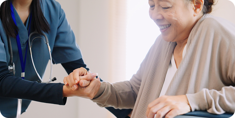 A female caregiver with a stethoscope helps a senior woman out of her wheelchair.