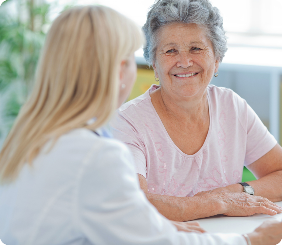 A happy senior woman with a doctor or caregiver sitting across from her.