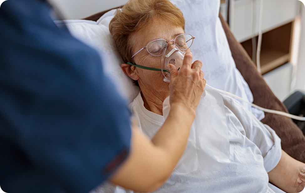 A healthcare professional assists an elderly patient wearing an oxygen mask while seated in a medical setting.
