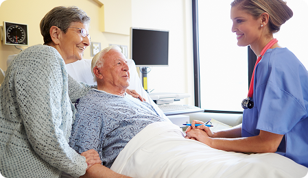 Senior couple interacting with a nurse in a hospital room, showcasing compassionate care and support during recovery.