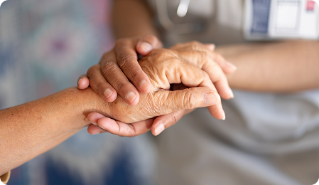 A healthcare professional gently holds the hands of a patient, conveying support and compassion in a clinical setting.