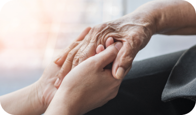 A close-up shot of a younger person's hands gently holding the wrinkled hands of an elderly person, showing care and compassion.
