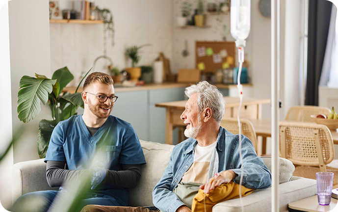 A healthcare professional engages in conversation with an elderly patient in a comfortable, well-lit home environment.