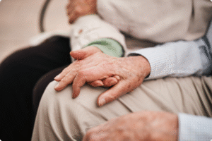 Elderly hands clasped together, symbolizing companionship and support in a serene setting, showcasing warm, gentle touch.