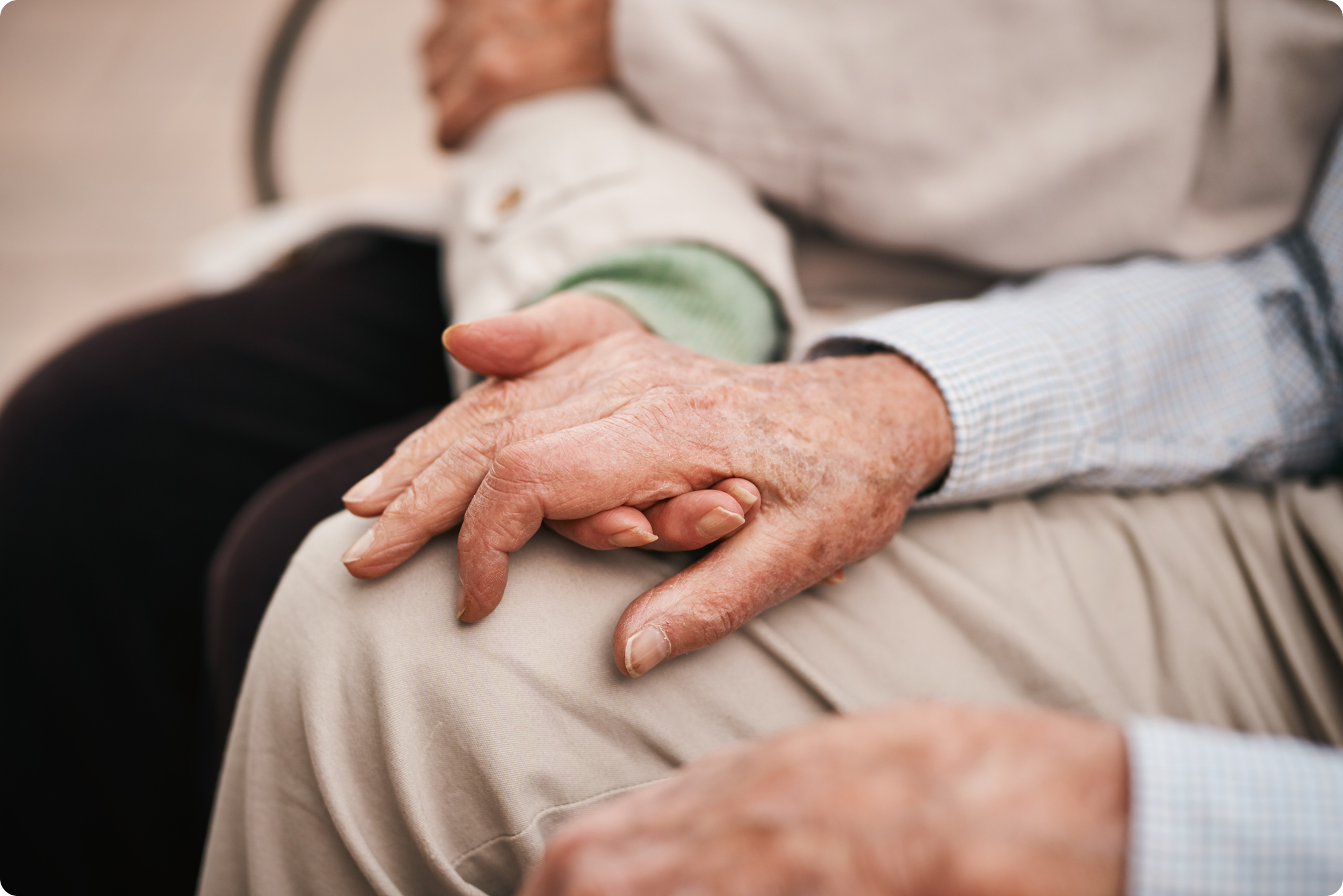 Elderly hands clasped together, symbolizing companionship and support in a serene setting, showcasing warm, gentle touch.