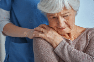 A caregiver gently comforts an elderly woman who appears to be in distress, showcasing a compassionate healthcare environment.