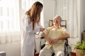 A healthcare professional in a white coat checks the blood pressure of a smiling elderly man in a wheelchair.