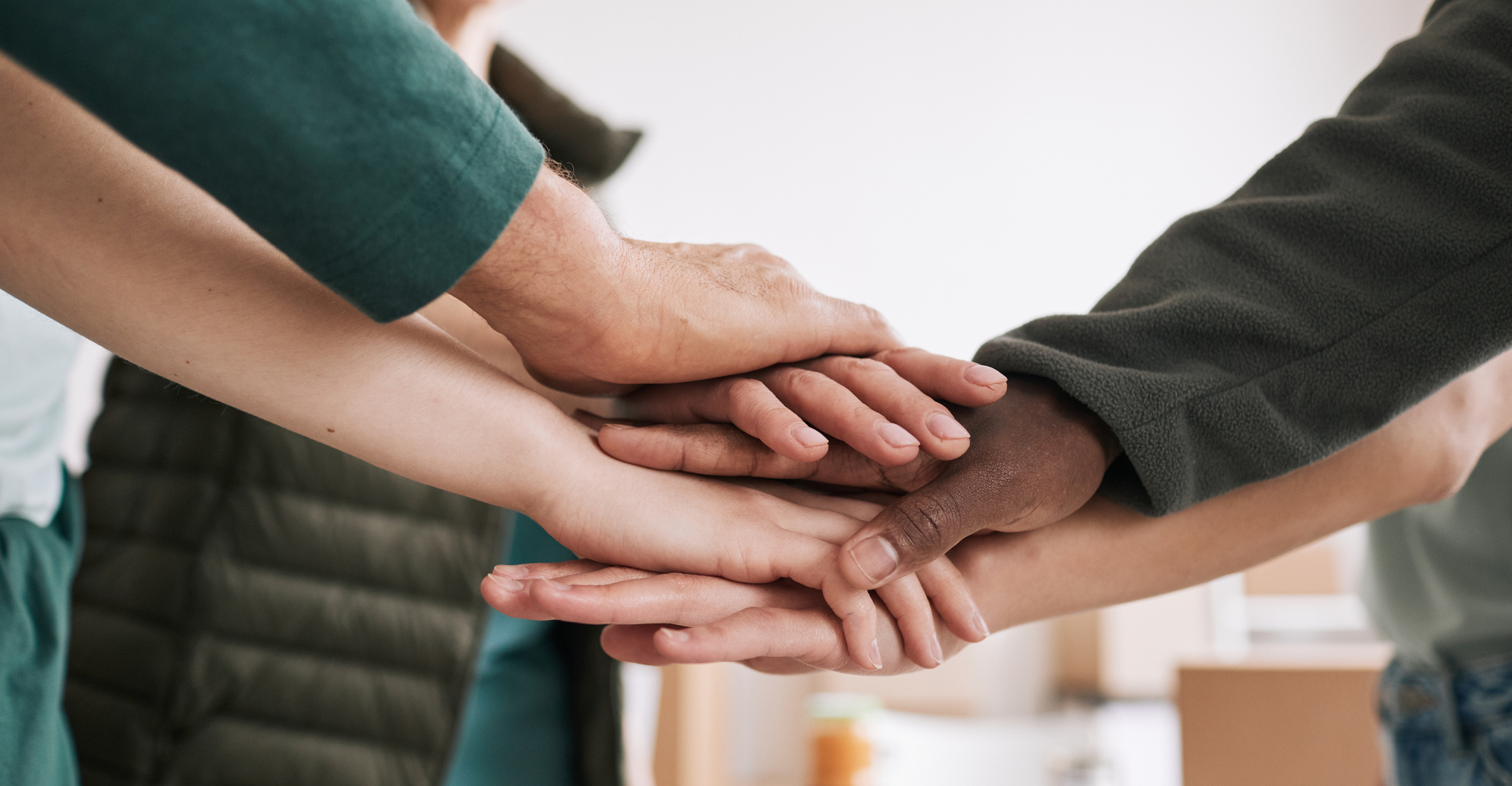 A diverse group of hands stacked together, symbolizing teamwork and collaboration in a professional setting.