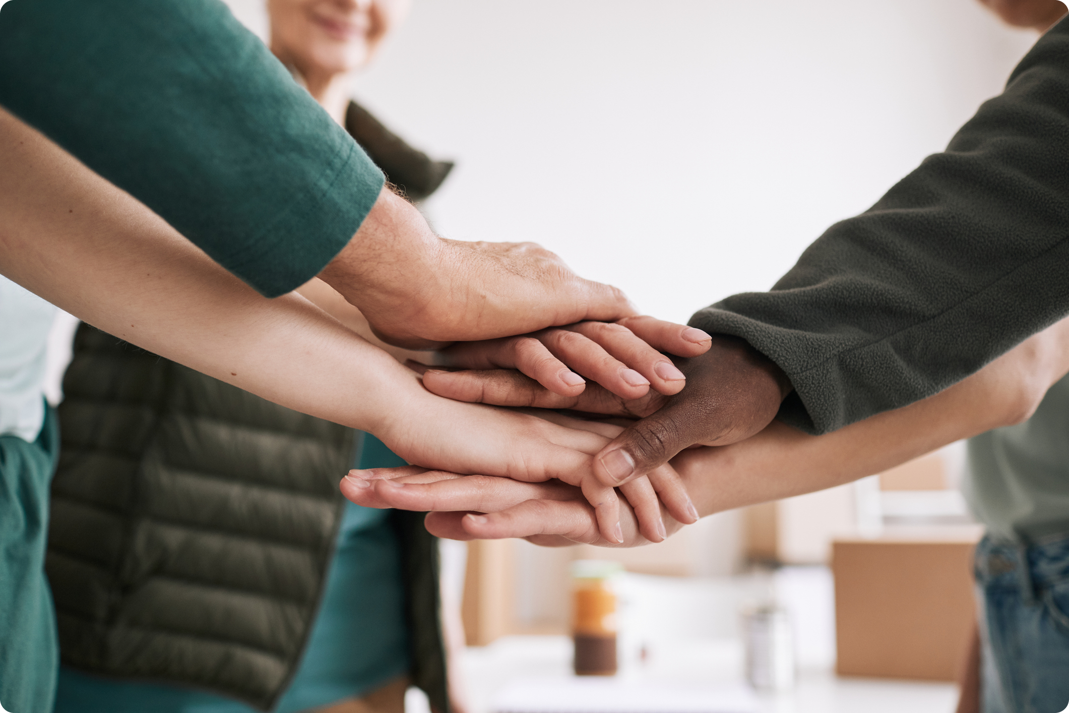 A diverse group of hands stacked together, symbolizing teamwork and collaboration in a professional setting.