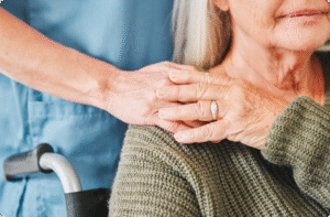A caregiver gently holds the hands of an elderly person, emphasizing compassion and connection in a warm environment.