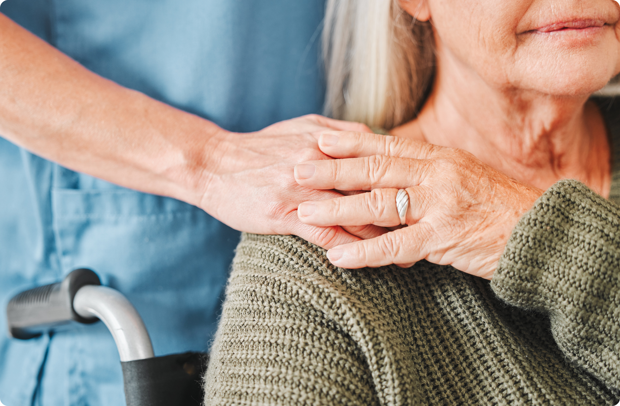A caregiver gently holds the hands of an elderly person, emphasizing compassion and connection in a warm environment.