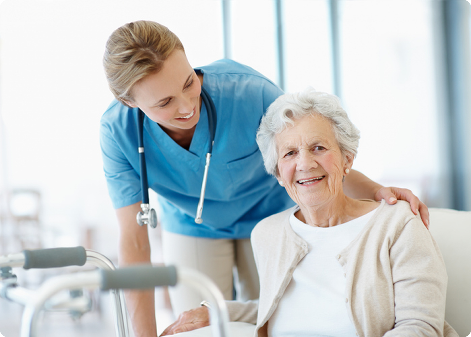 A smiling senior woman is accompanied by a compassionate caregiver in a bright, healthcare setting.