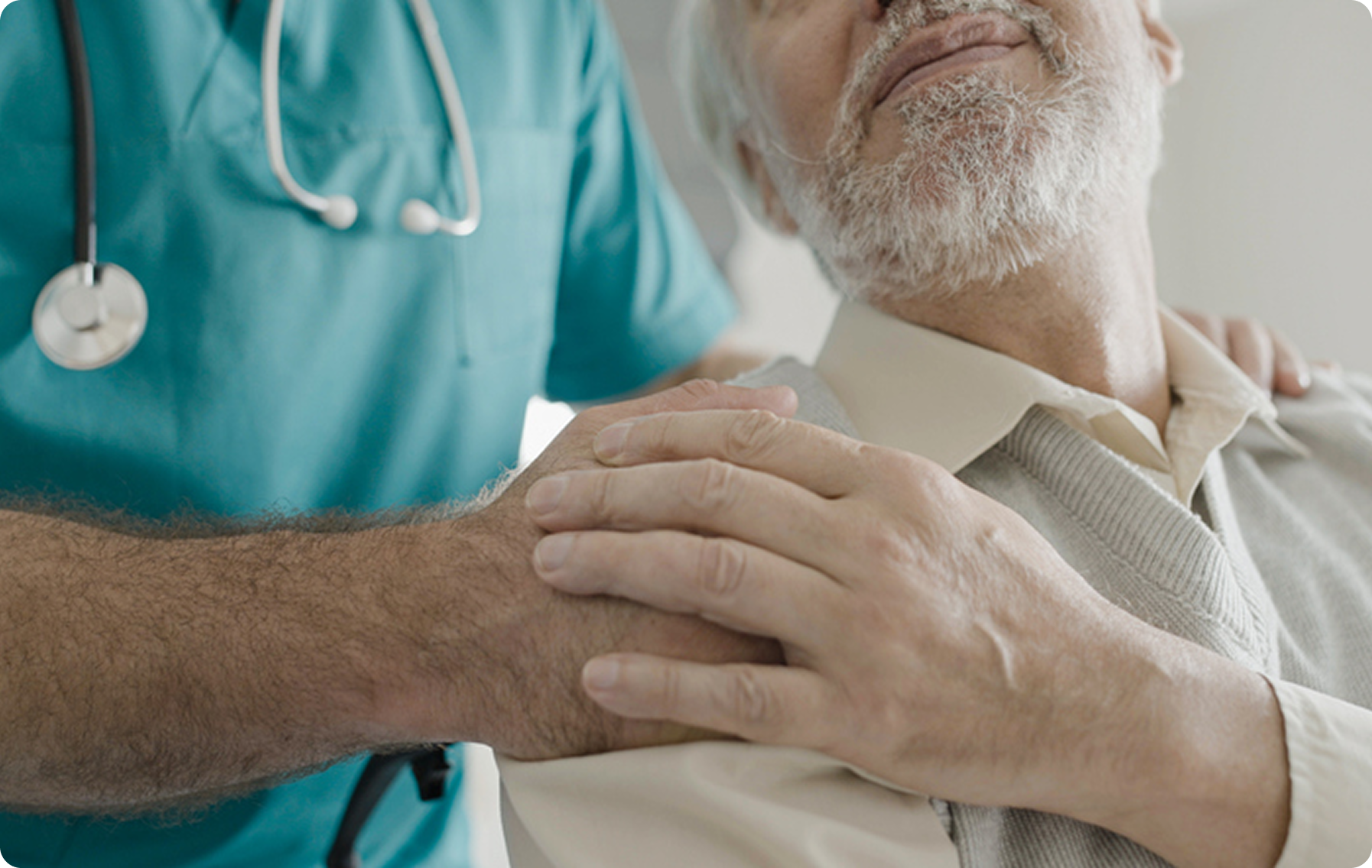 A healthcare professional gently holds the hand of an elderly patient in a comforting environment.