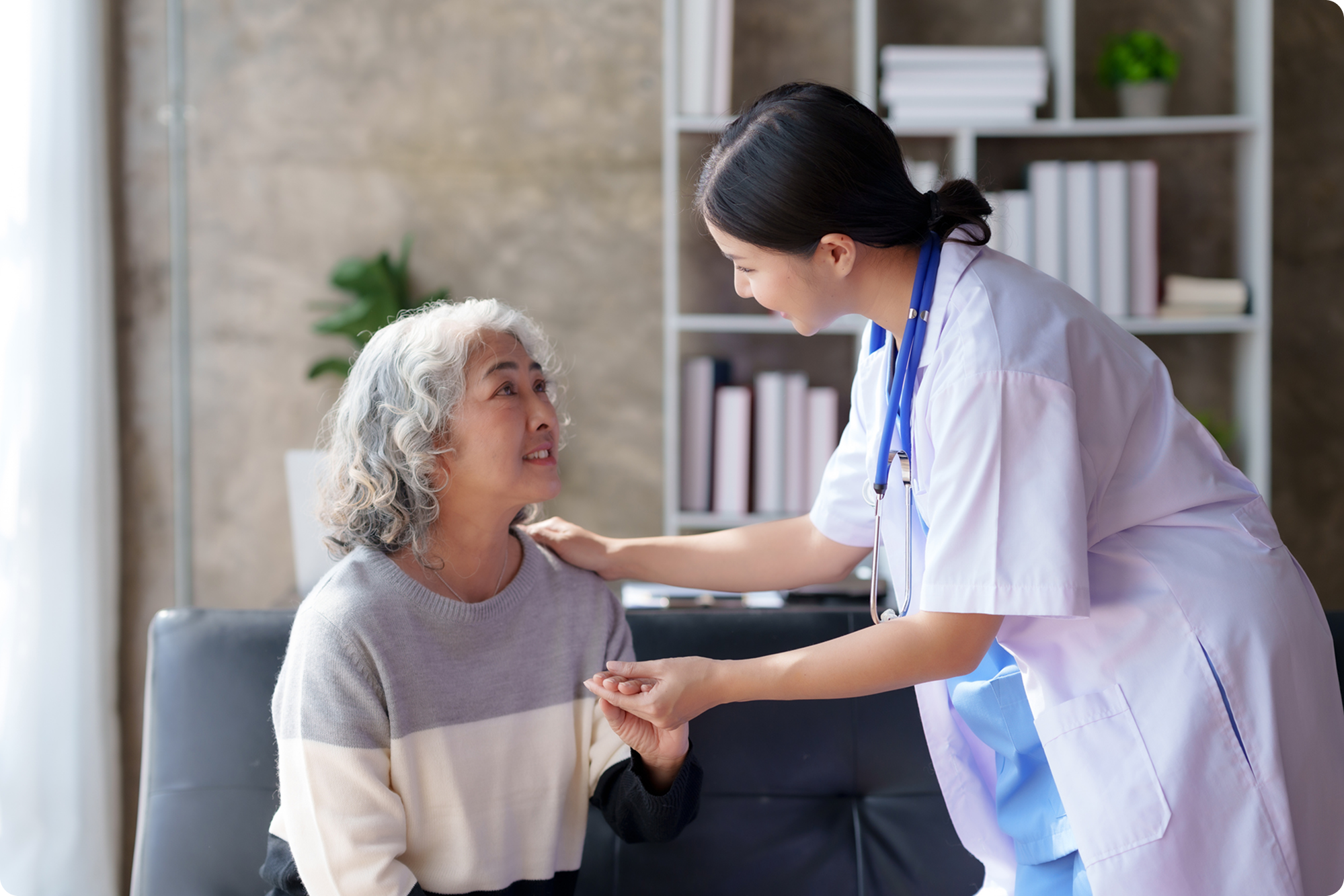 A healthcare professional interacts warmly with an older woman in a modern waiting area, showcasing compassionate care.