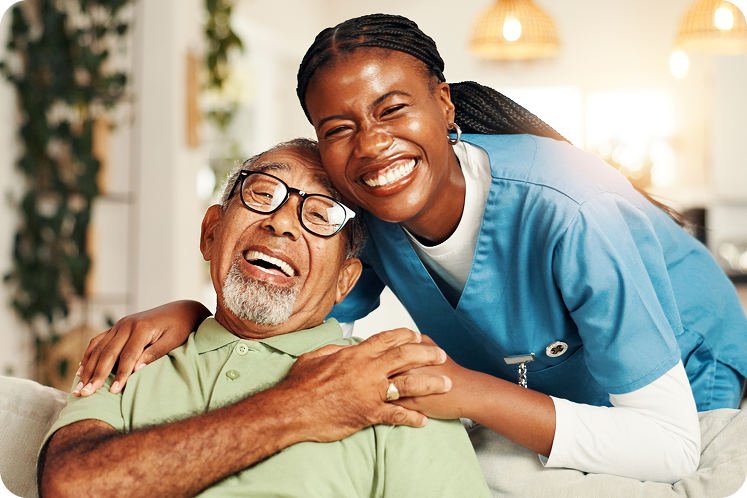 Smiling healthcare worker embraces elderly patient in a cozy, well-lit living space, showcasing a supportive environment.