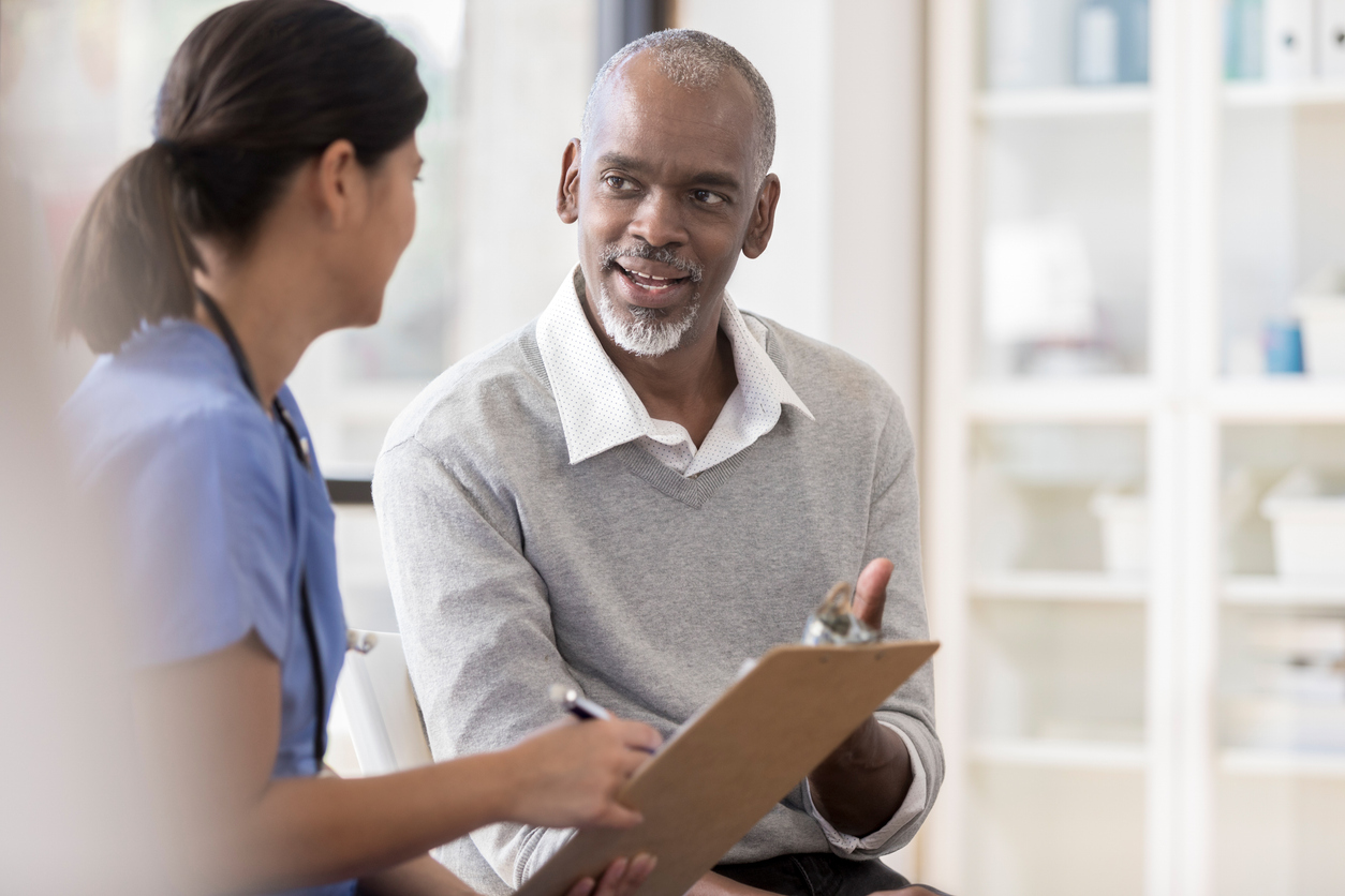 A healthcare professional consults with a patient in a well-lit medical office, discussing health-related information.